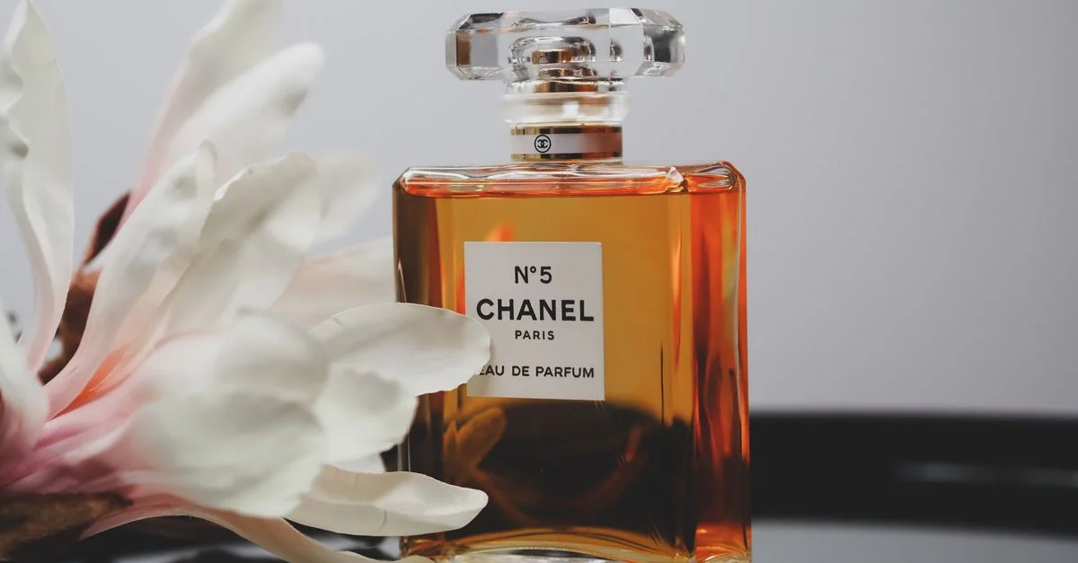 Botella de perfume Chanel No. 5 con una flor delicada, que refleja elegancia y lujo.