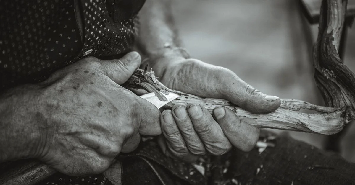 Primer plano de manos tallando madera hábilmente, mostrando la artesanía.