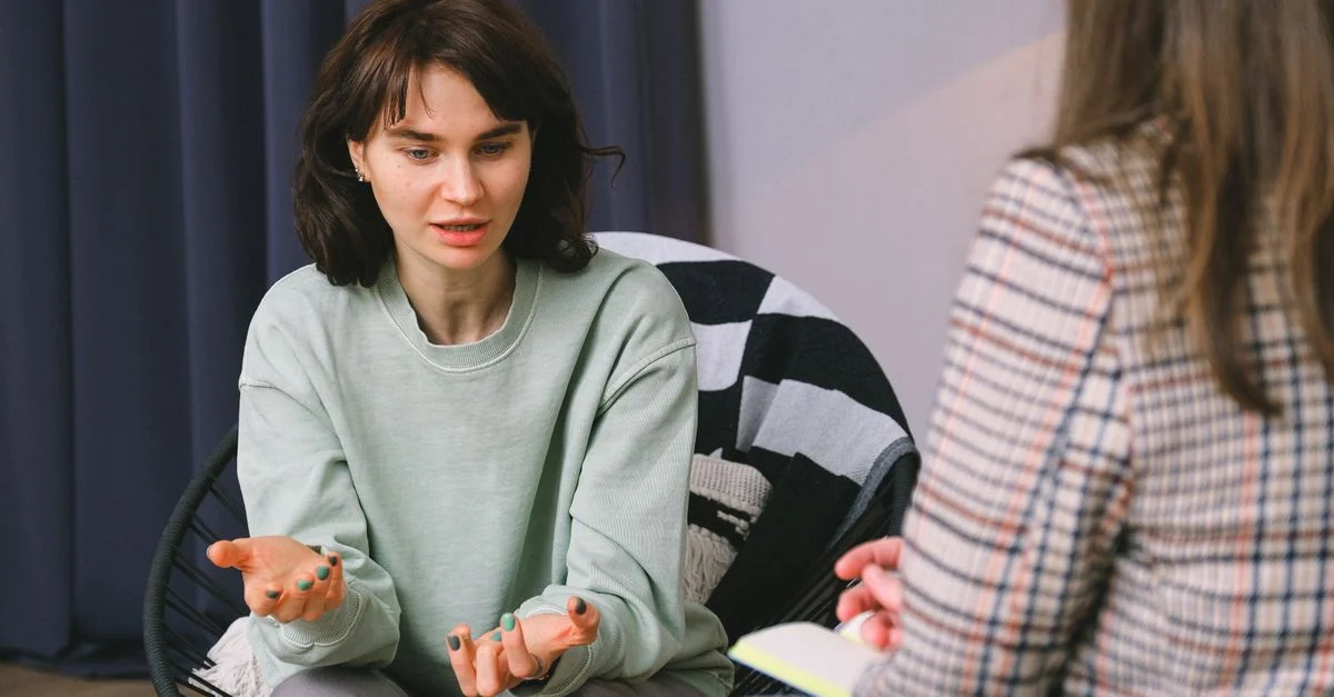 Dos mujeres teniendo una discusión reflexiva en una sesión de terapia en un entorno acogedor.
