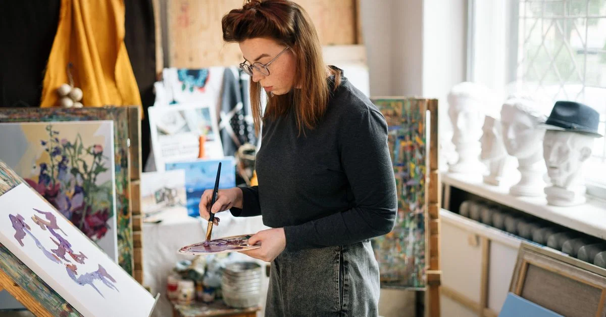 Artista mujer pintando en un lienzo en un estudio brillante y soleado. Ambiente creativo y enfocado.