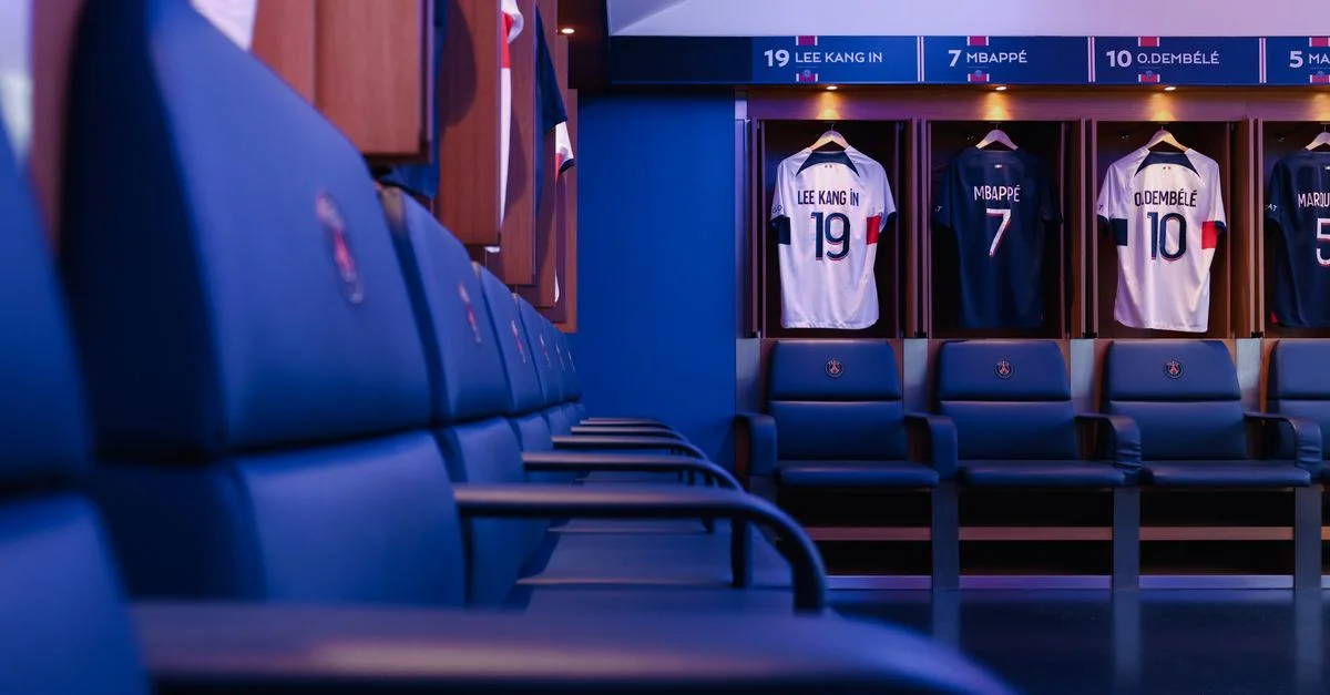 Vestuario de fútbol profesional en París con camisetas de los jugadores expuestas.