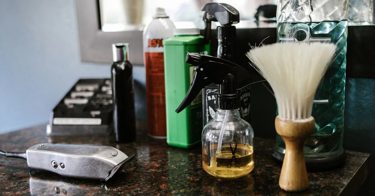 Gros plan sur des outils de barbier sur le comptoir, y compris des tondeuses, un flacon vaporisateur et une brosse dans un salon de coiffure élégant.